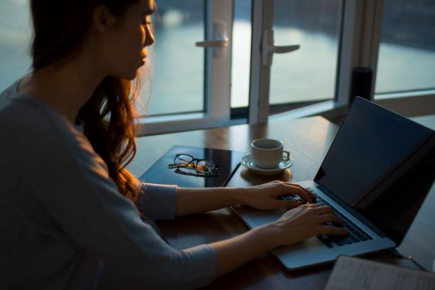 woman working on computer in a dark room with a window