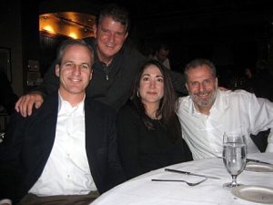 Group of two women and two men at a white table posing for a photo.