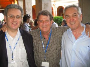 Three men smiling and posing for a photo outside at a conference.