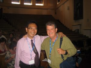 Man in pink shirt and a man in a green shirt posing for a photo at a conference.