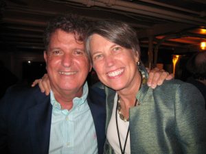 Man and woman smiling at the camera at a conference.