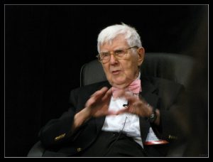 Dr. Aaron Beck presenting, seated in a chair.