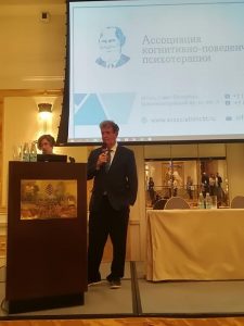 Psychologist giving a presentation with a screen behind him.