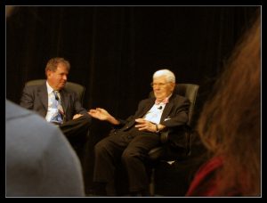 Two men seated on a stage discussing psychology.