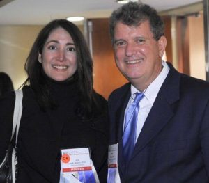 Man and woman in formal attired posing for photo at a conference.