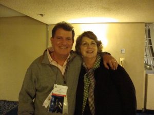 Man and woman posing in friendly manner for a photo at a conference